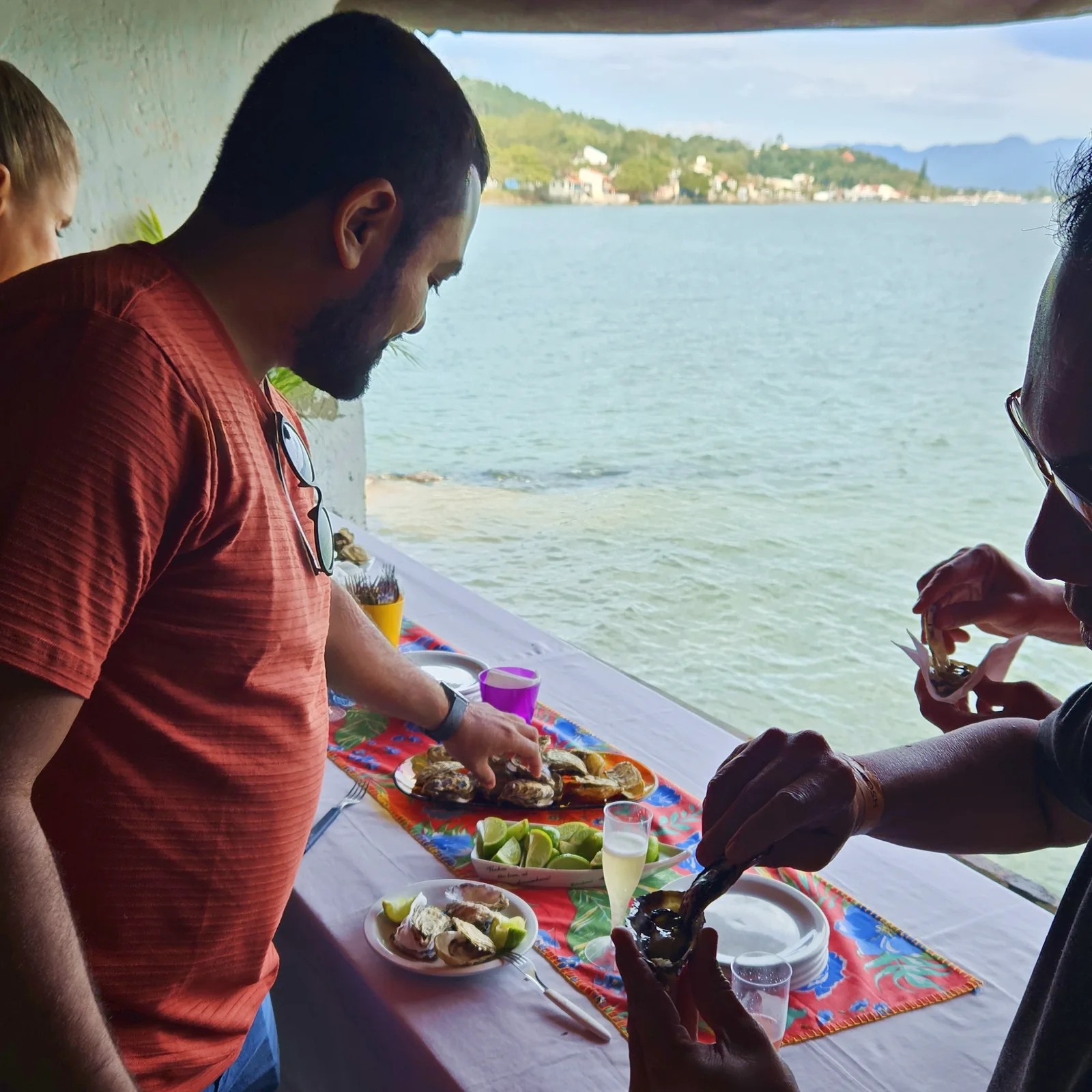 Grupo pequeno provando ostras à mesa, com vista para a baía, no Ostra Xperience VIP